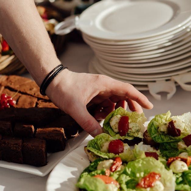 A person is reaching for a salad on a plate.