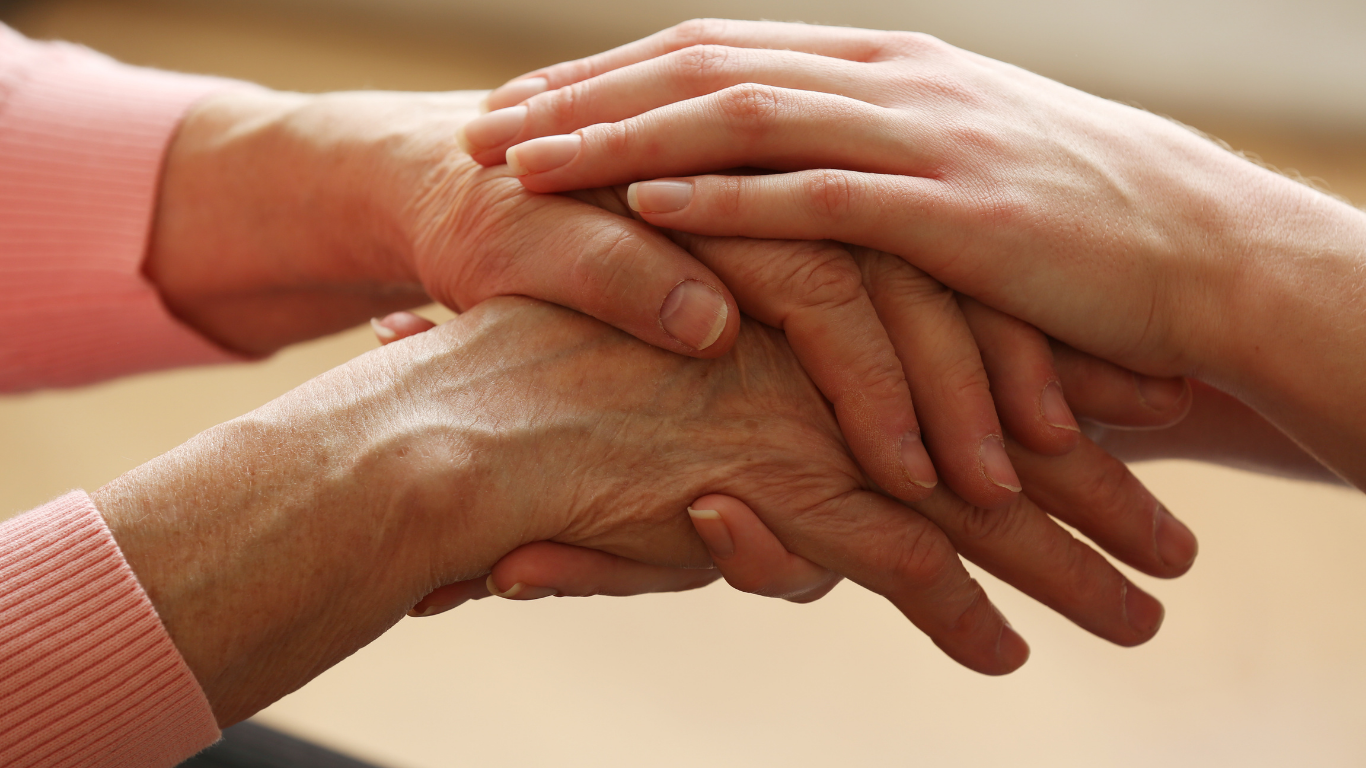 Three hands stacked together in a supportive gesture on a beige background