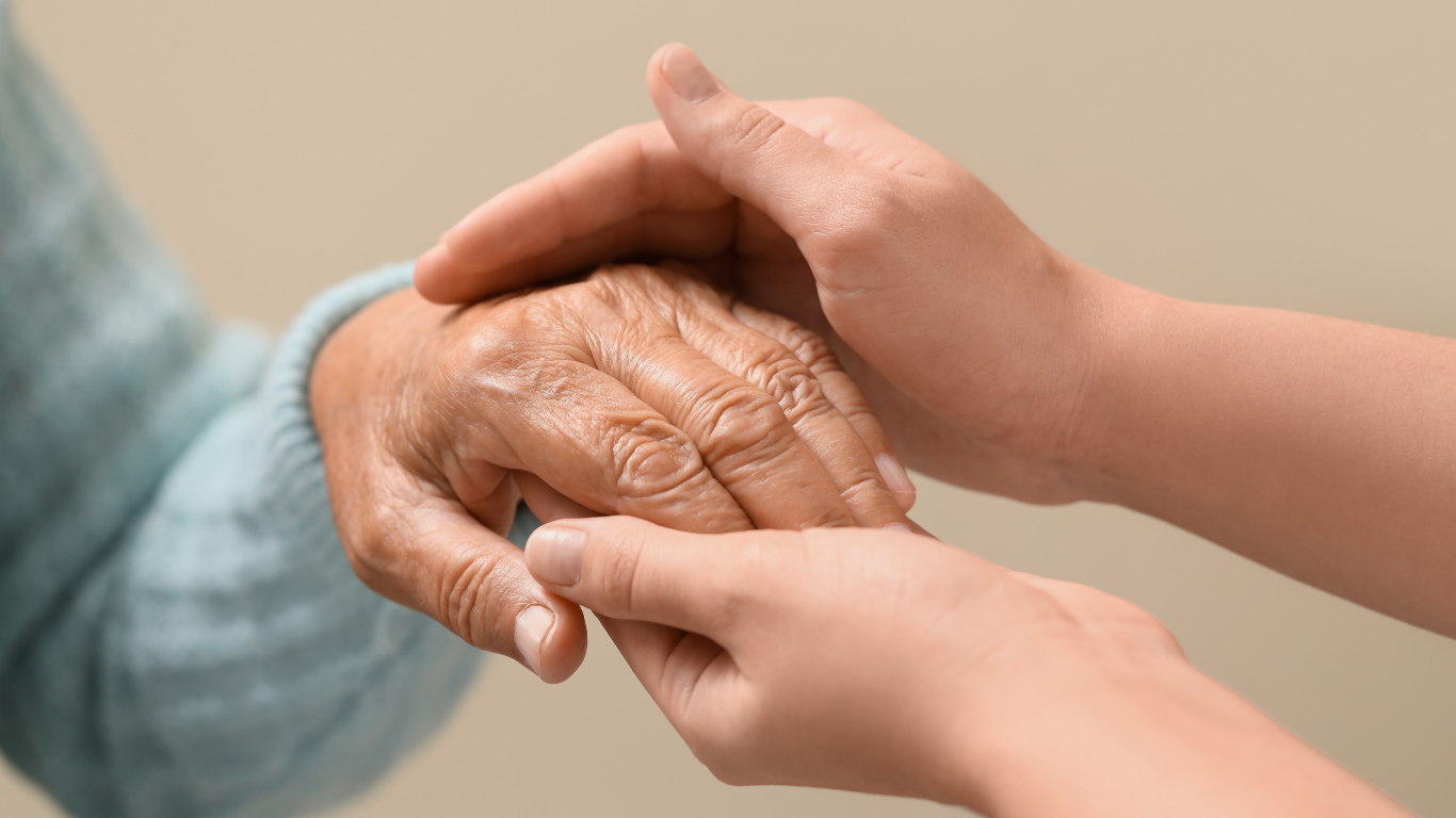 Hands gently holding an older person’s hand in a comforting gesture