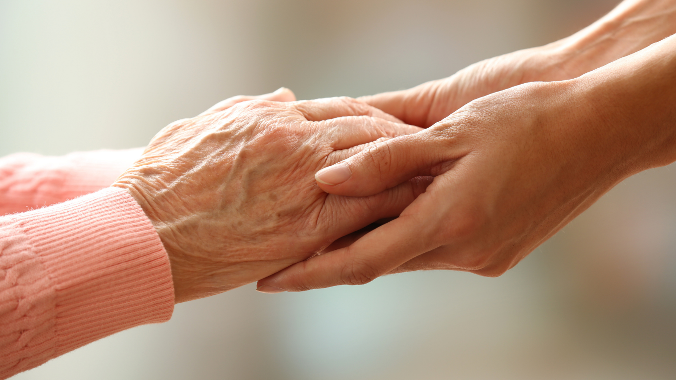 Two hands gently holding each other in a close-up, showing care and support.
