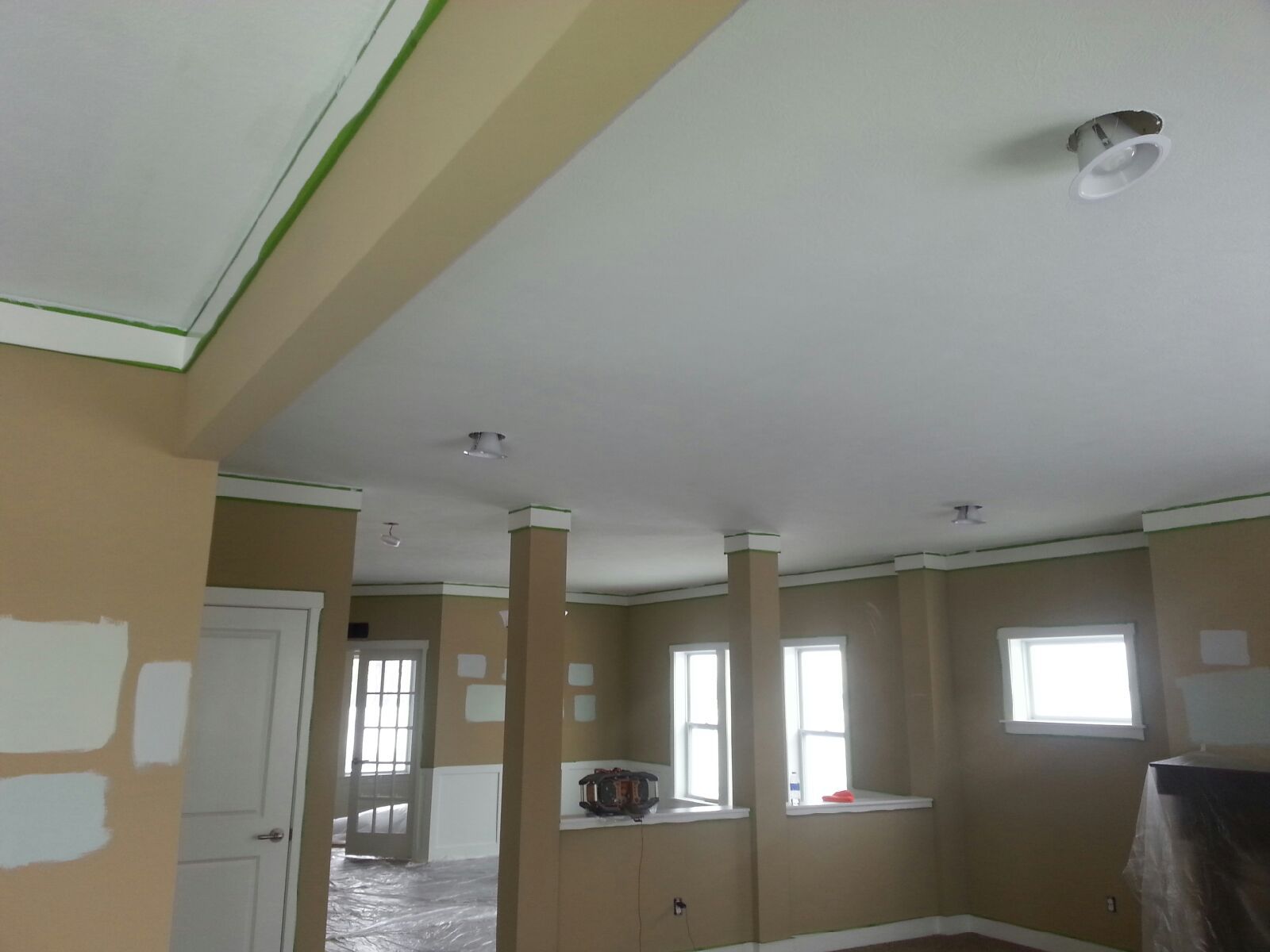 Interior of a room under renovation; beige walls, white ceiling, pillars, and windows.