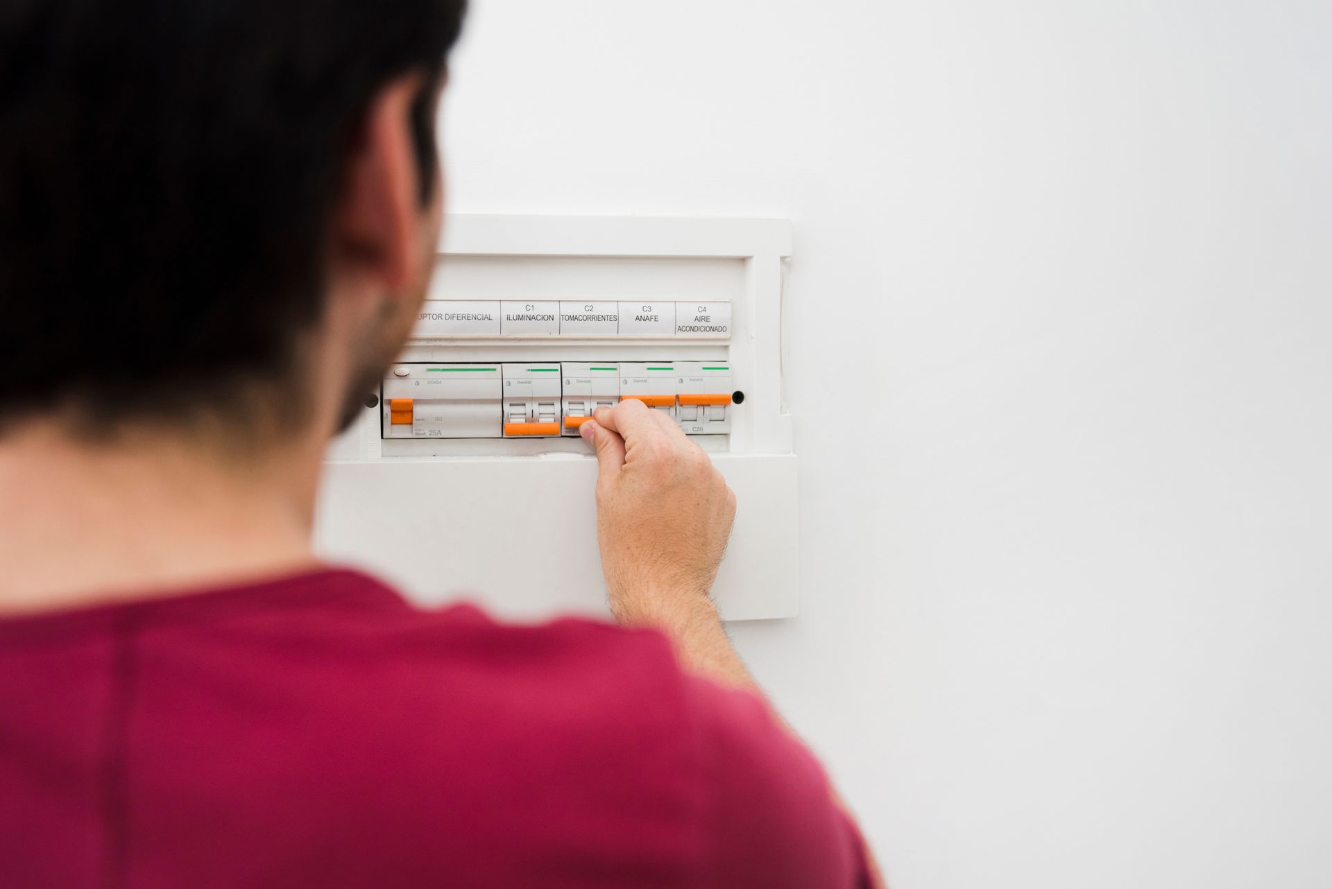 Person turning a circuit breaker on in a white electrical panel.