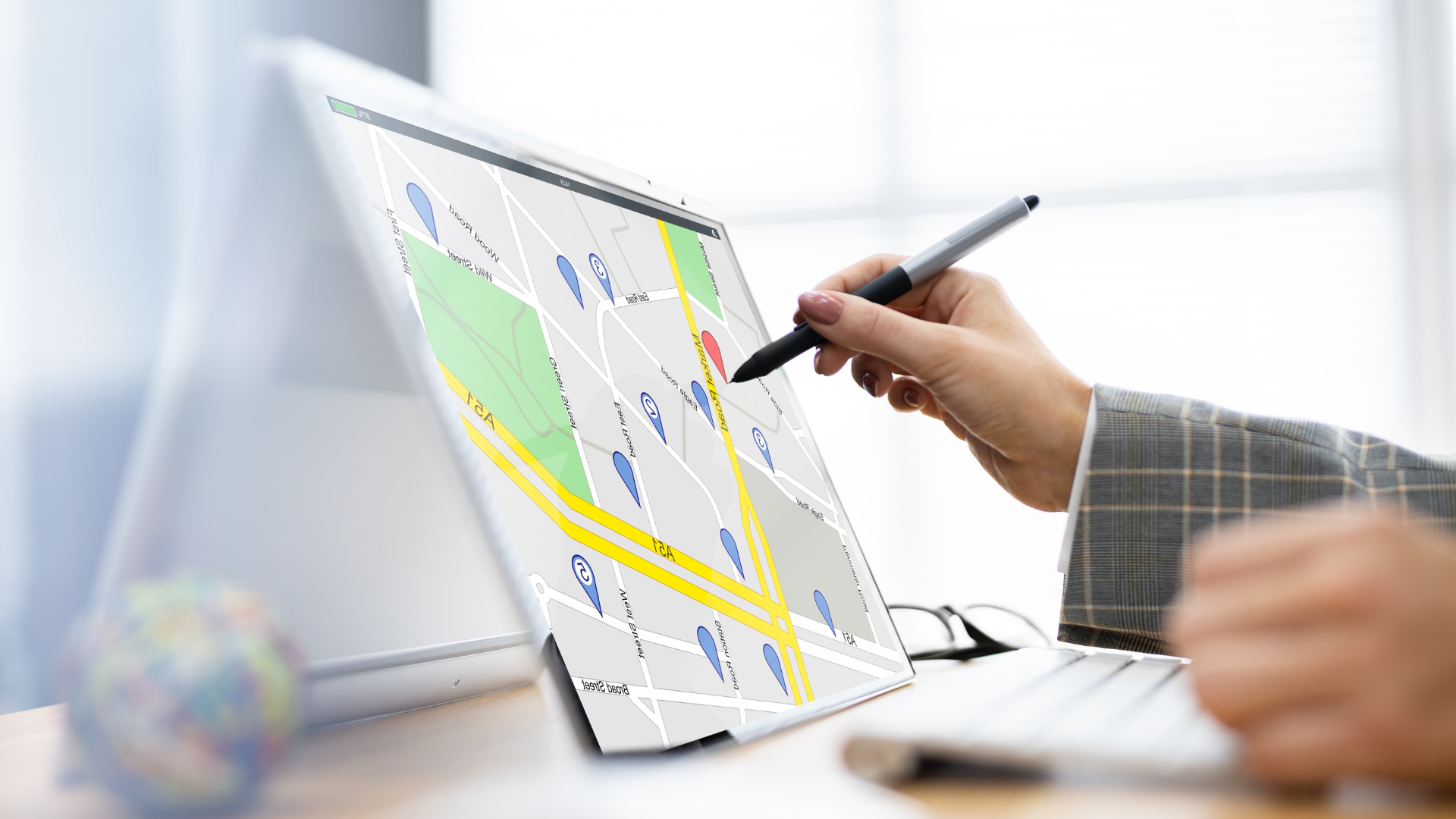 A person is using a pen to draw a map on a laptop computer.