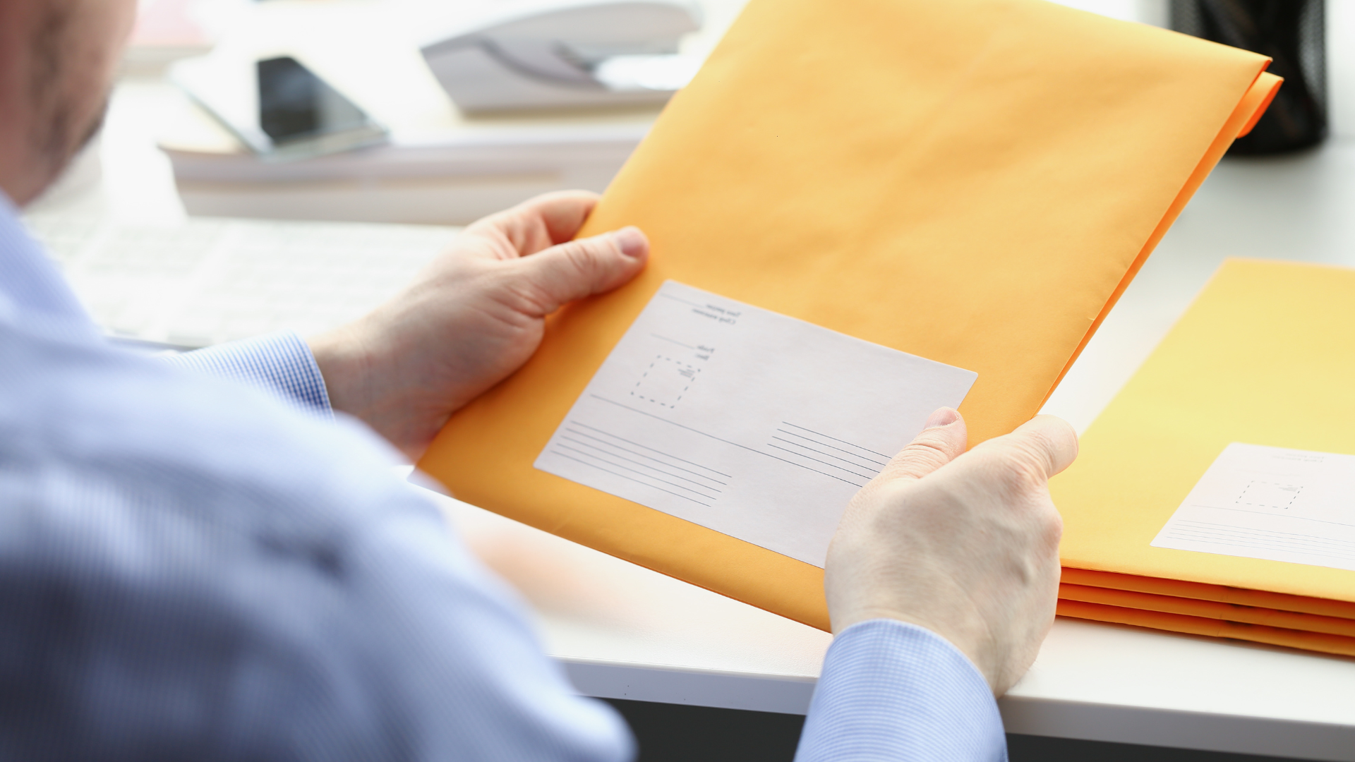 A man is holding an envelope with a sticker on it.
