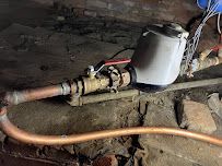 Old water pump with hoses and pipes on a muddy floor in a dim utility space