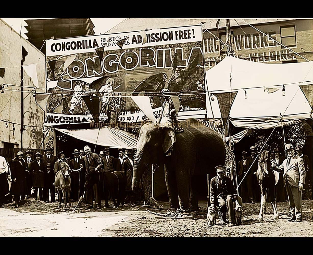 A sepia-toned vintage photo of an elephant standing before a large sign for a