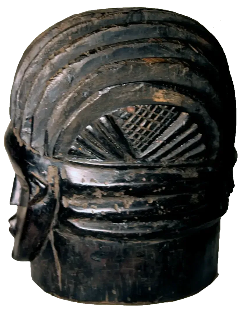 A dark-toned, carved wooden mask with a segmented, tiered hairstyle and patterned, etched details on the sides.