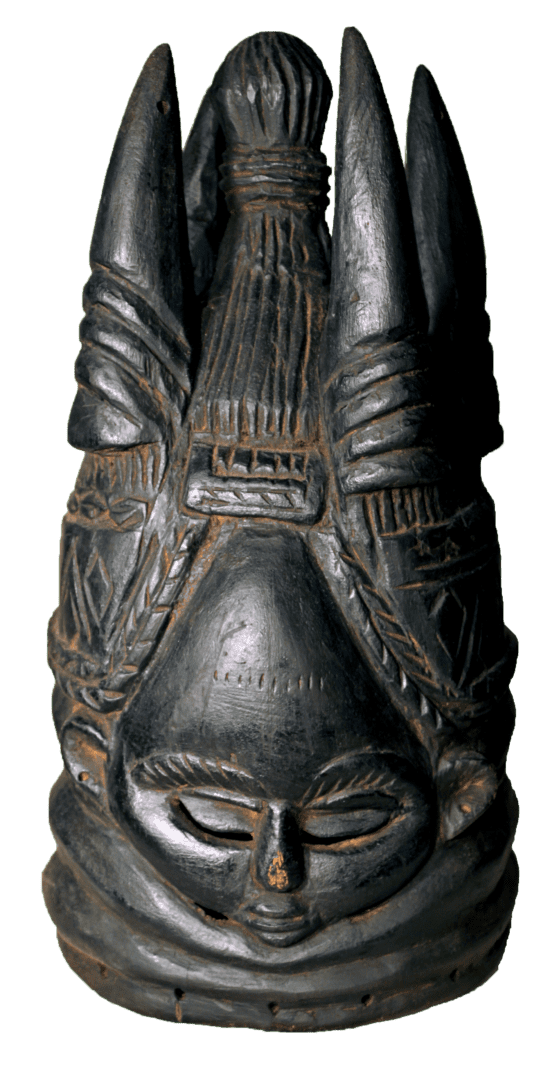 A dark, carved wooden helmet mask with a serene face, elaborate braided hairstyle, and tall, pointed structural elements.