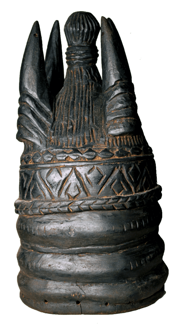 A carved, dark wooden helmet mask with a cylindrical base, geometric patterned middle, and three pointed vertical crests.