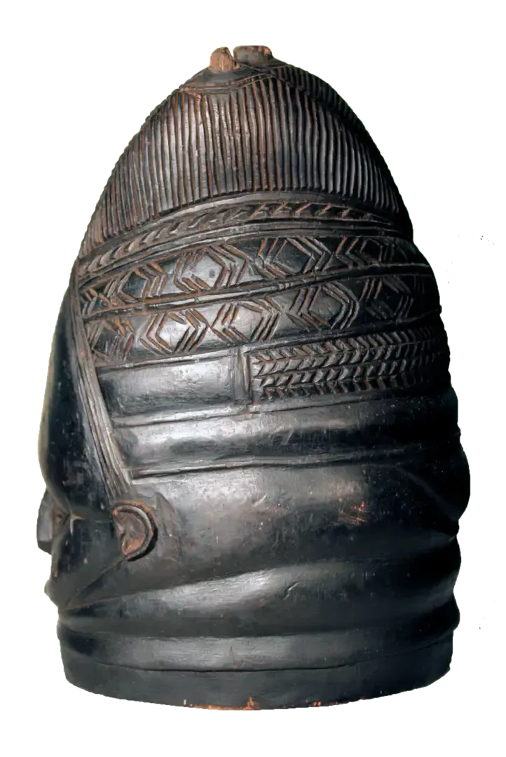 A carved dark wood mask with a high, domed top and intricate geometric patterns on its upper section.