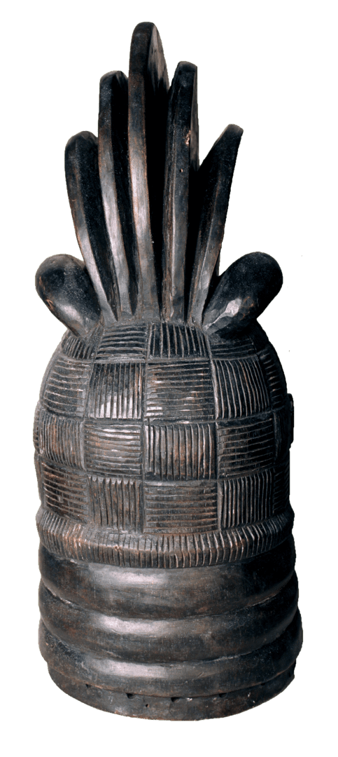 A carved wooden headdress with a checkered, patterned dome and a vertical, fan-like crest at the top.