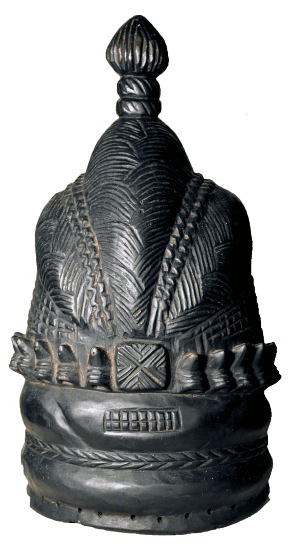 A black, intricately carved wooden headdress with textured patterns, a central square motif, and a knob-shaped finial.