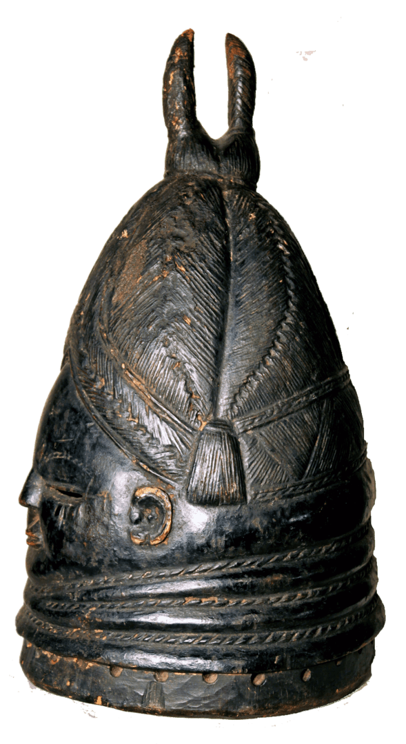 A dark, carved wooden helmet mask with a dome-shaped top, ridged base, and a bifurcated finial against a white background.