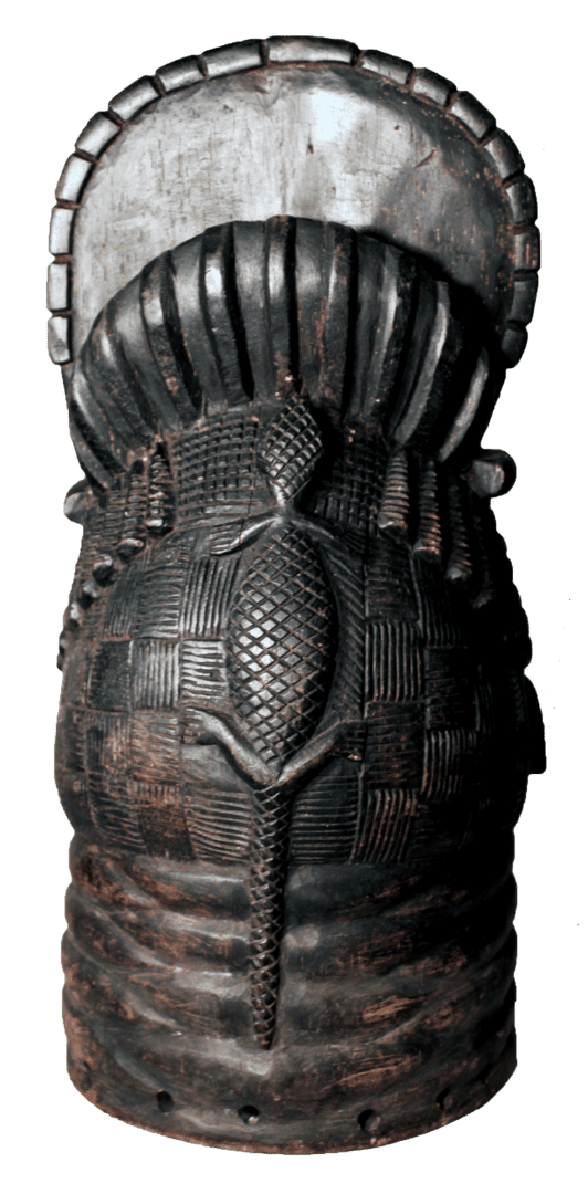 A dark, cylindrical wooden mask with a metallic top, intricate textured carvings, and a central lizard-like relief.