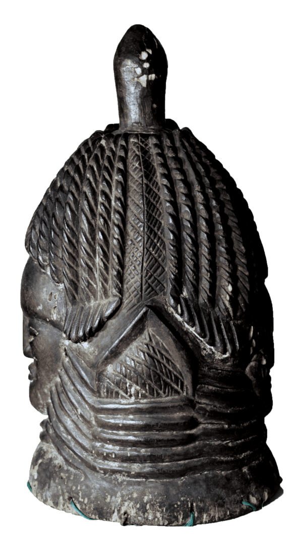 A carved, dark wooden mask depicting a stylized head with intricate hair braiding and a central vertical projection.