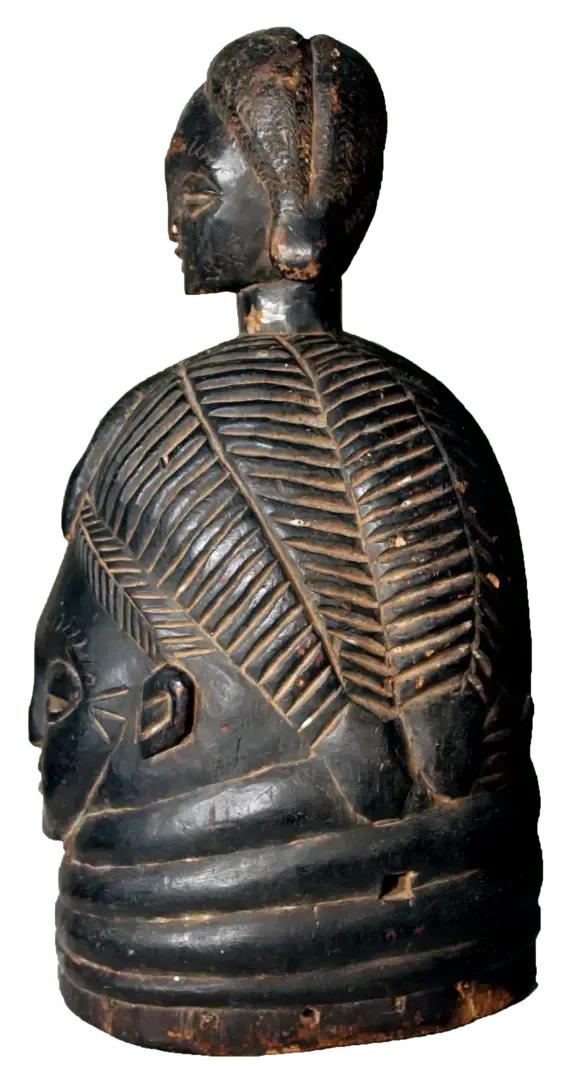 A dark, polished wooden sculpture of a head with detailed, leaf-like carved hair and multiple horizontal neck rings.