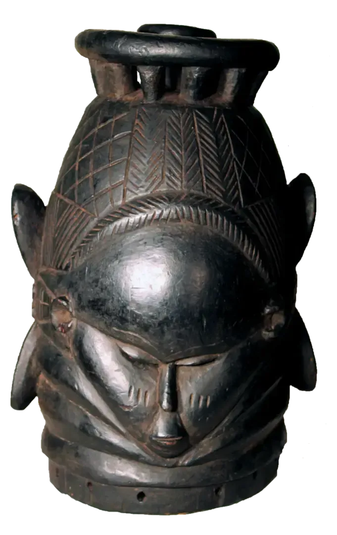 A dark, carved wooden Mende Sowei helmet mask with intricate geometric patterns, stylized features, and neck rings.