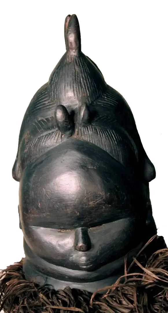 A dark, polished wooden Mende Sowei helmet mask with a stylized, high-coiffed hairstyle and a raffia collar.