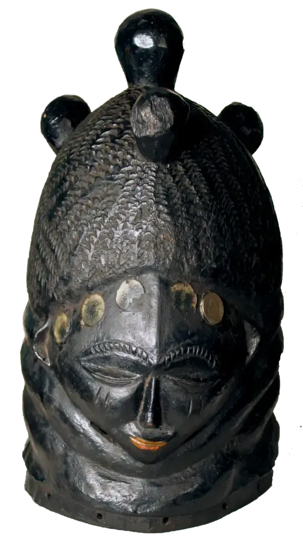 A dark, carved wooden helmet mask featuring an ornate textured hairstyle with small spherical protrusions on top.