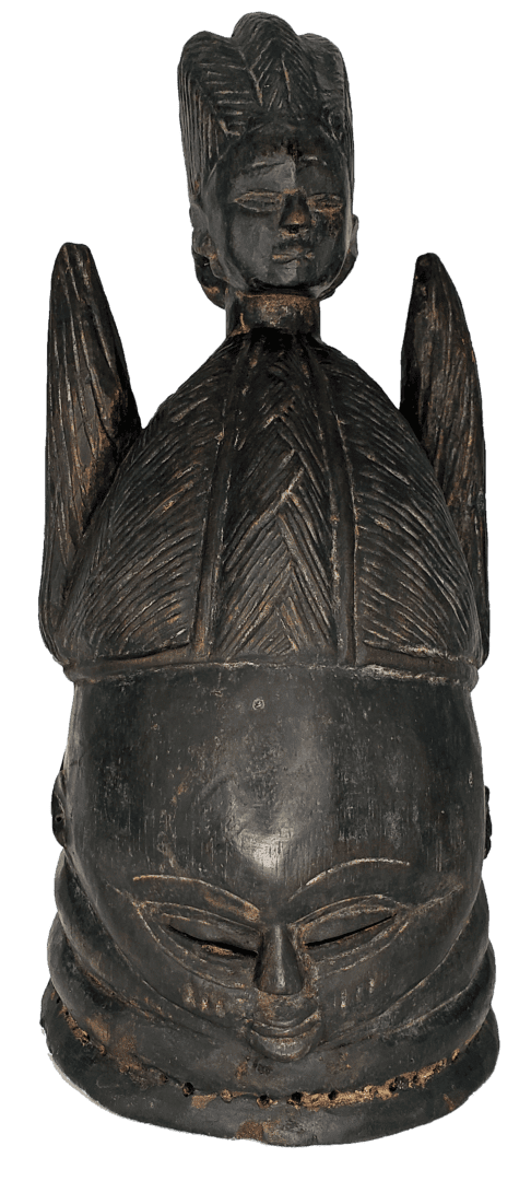 A dark, carved wooden helmet mask featuring a central face, a dome-like headpiece with vertical ridges, and side projections.
