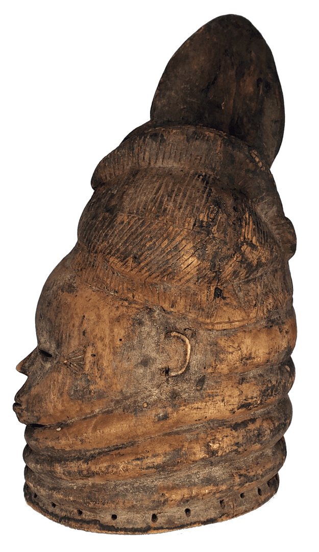 A weathered, carved wooden mask in profile, featuring elaborate tiered neck rings and a prominent, rounded hairstyle.