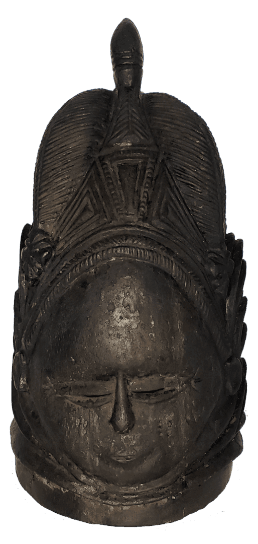 A dark, carved wooden mask with an intricate headdress featuring a central upright figure and geometric patterns.