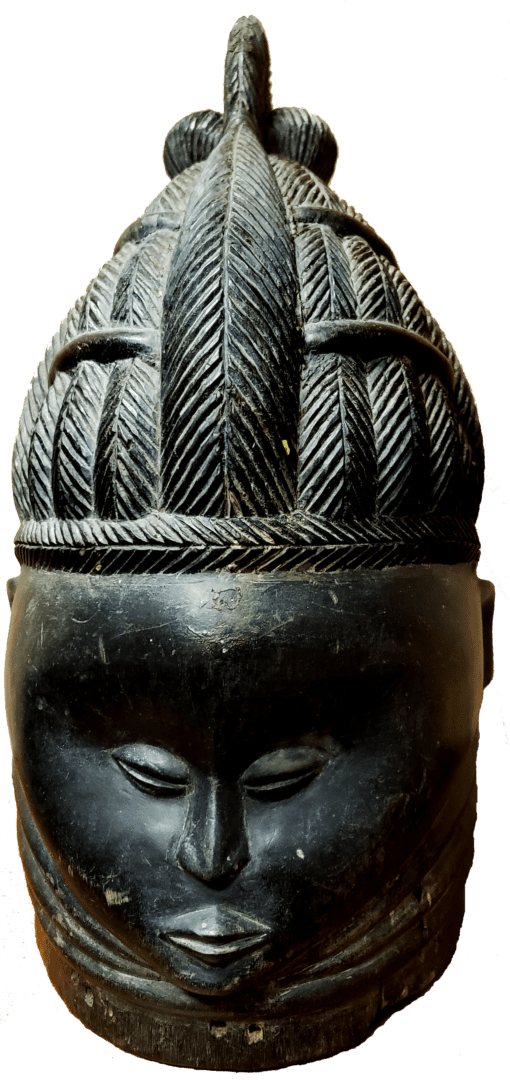 A dark, carved wooden mask with a serene facial expression and an elaborate, textured headdress featuring vertical ridges.