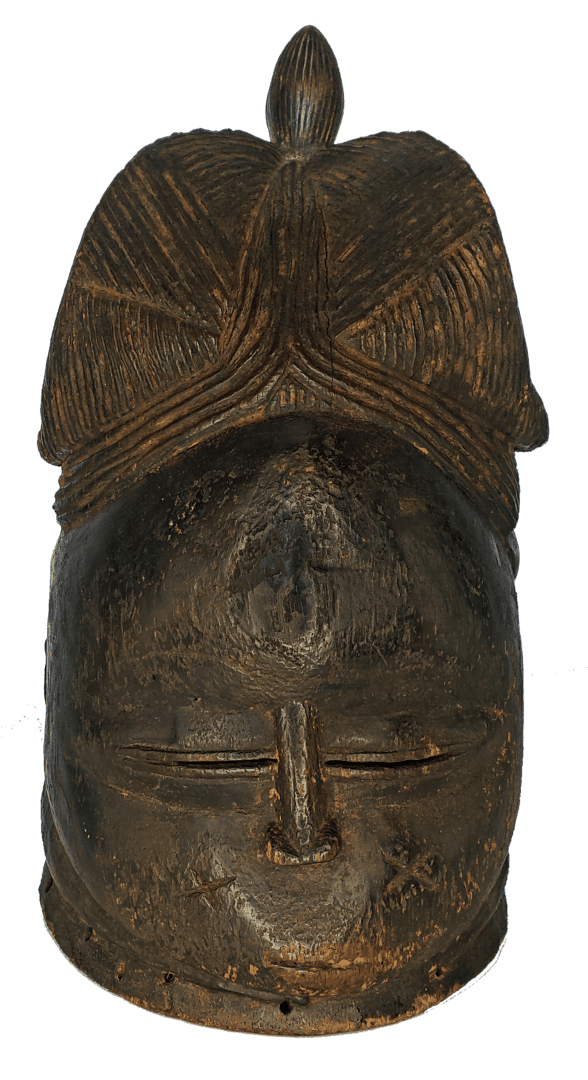A dark-toned, carved wooden mask with a textured, rounded headdress and narrow, horizontal slit eyes.