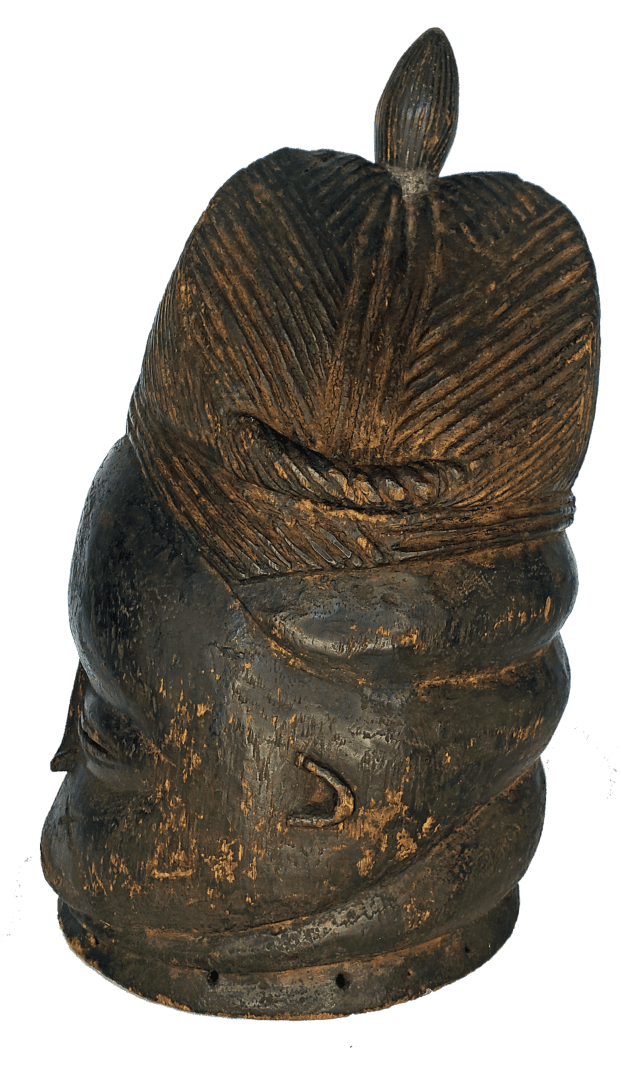 A dark, carved wooden head featuring intricate, textured hair patterns and a small, pointed protrusion on top.
