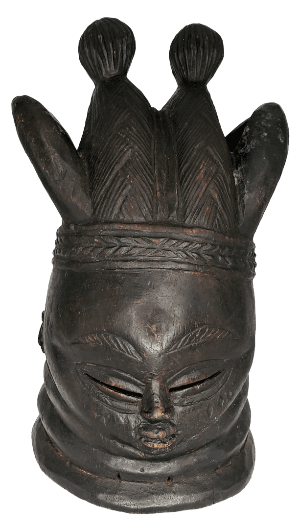 A dark, carved wooden mask with an ornate, multi-pointed headdress, downcast eyes, and neck rings.