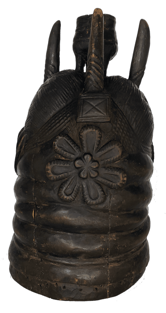 A dark wooden Senufo helmet mask with ribbed textures, a carved flower motif, and three upright horn-like protrusions.