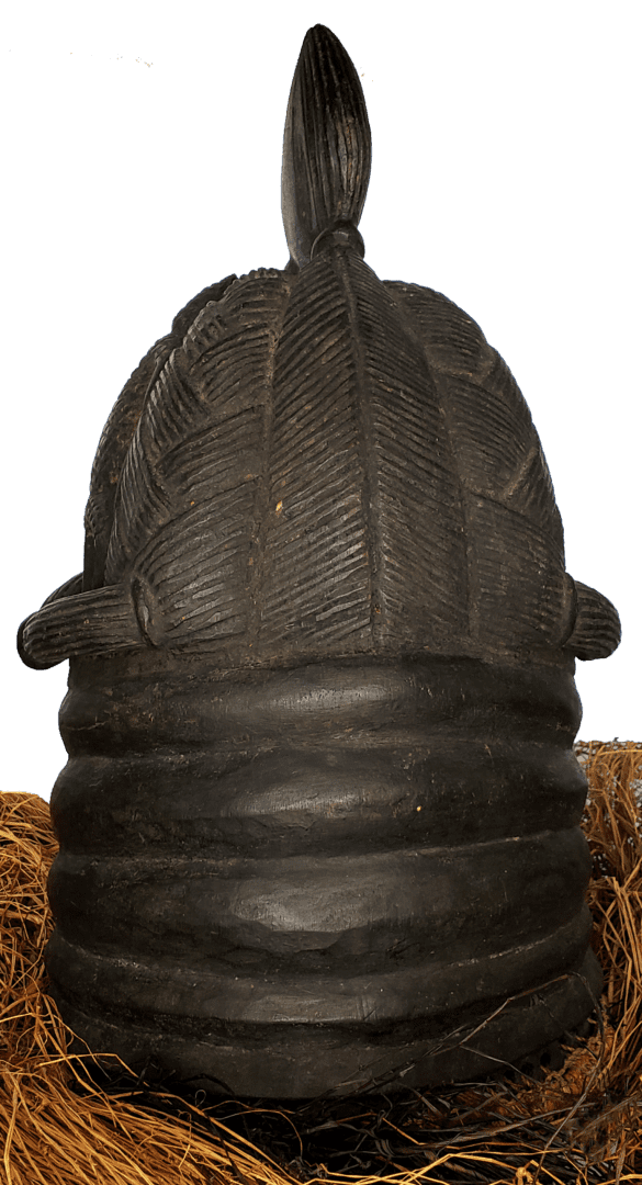 A dark, carved wooden helmet or headpiece featuring textured, leaf-like panels on top and layered, ridged bands at the base.