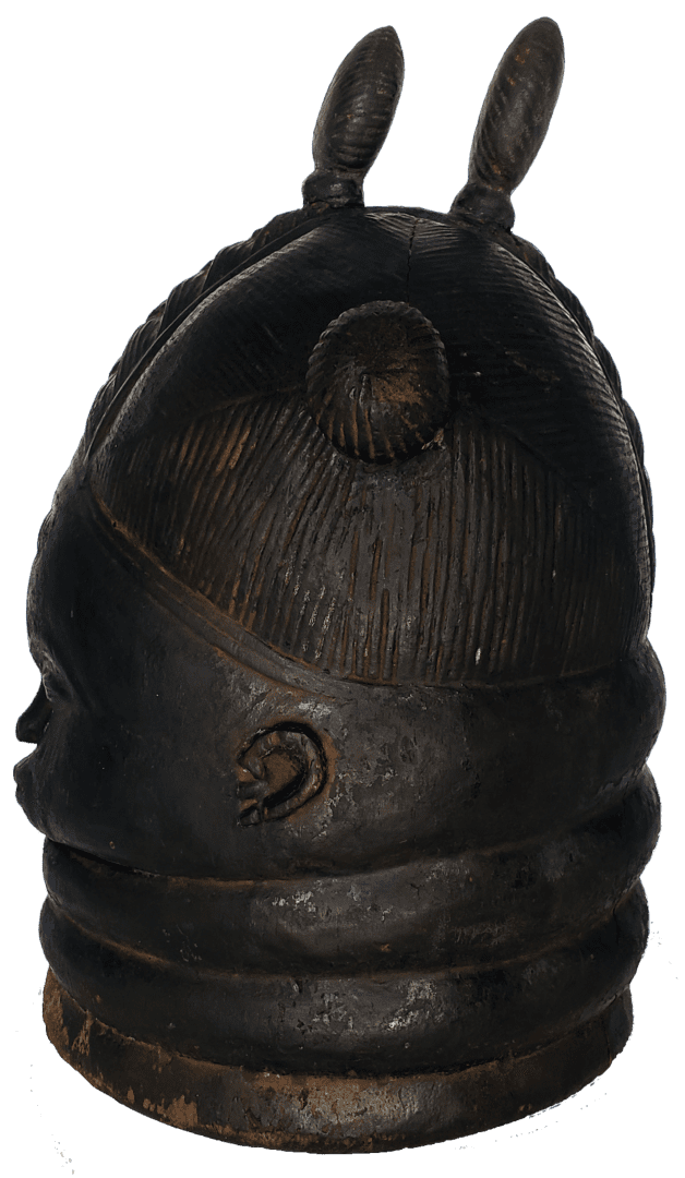 A dark, carved wooden mask with stacked neck rings, elaborate hair detail, and two prominent horn-like projections on top.