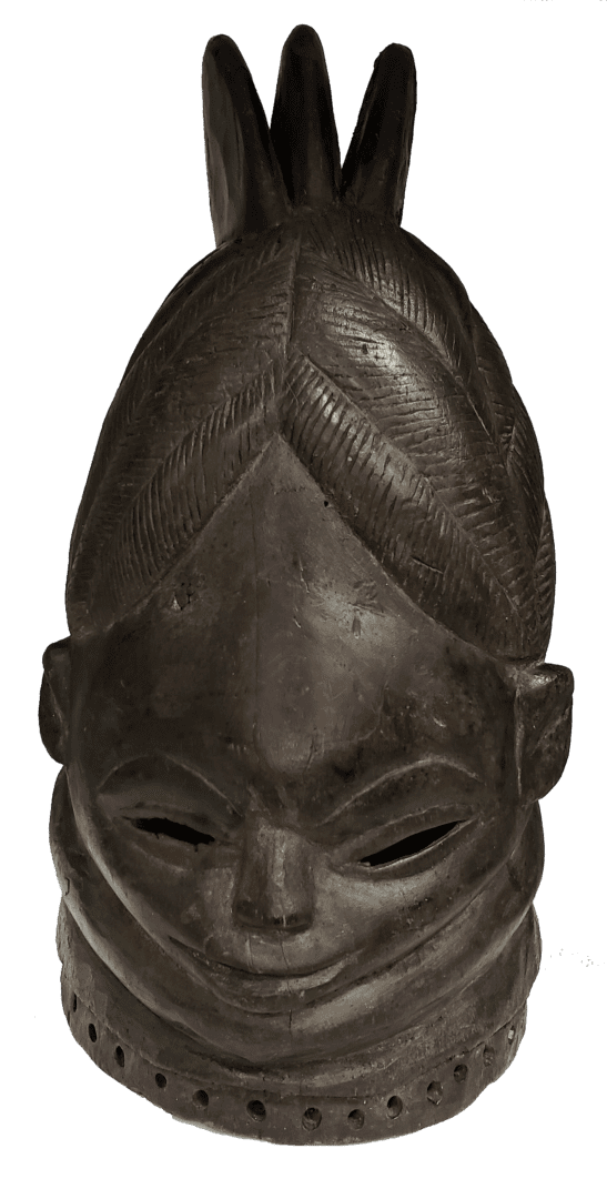 A dark, carved wooden helmet mask with a triple-pointed crest, stylized facial features, and a perforated base.
