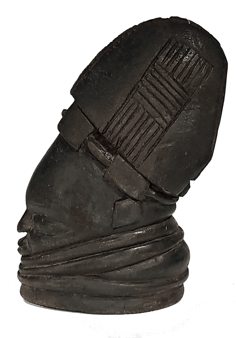 A dark carved wooden sculpture of a head with a patterned, crested headdress and layered neck rings.
