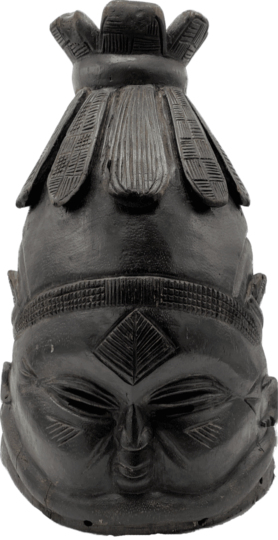 A dark, carved wooden mask with an intricate, tall, petal-shaped headdress and a detailed geometric pattern on the forehead.