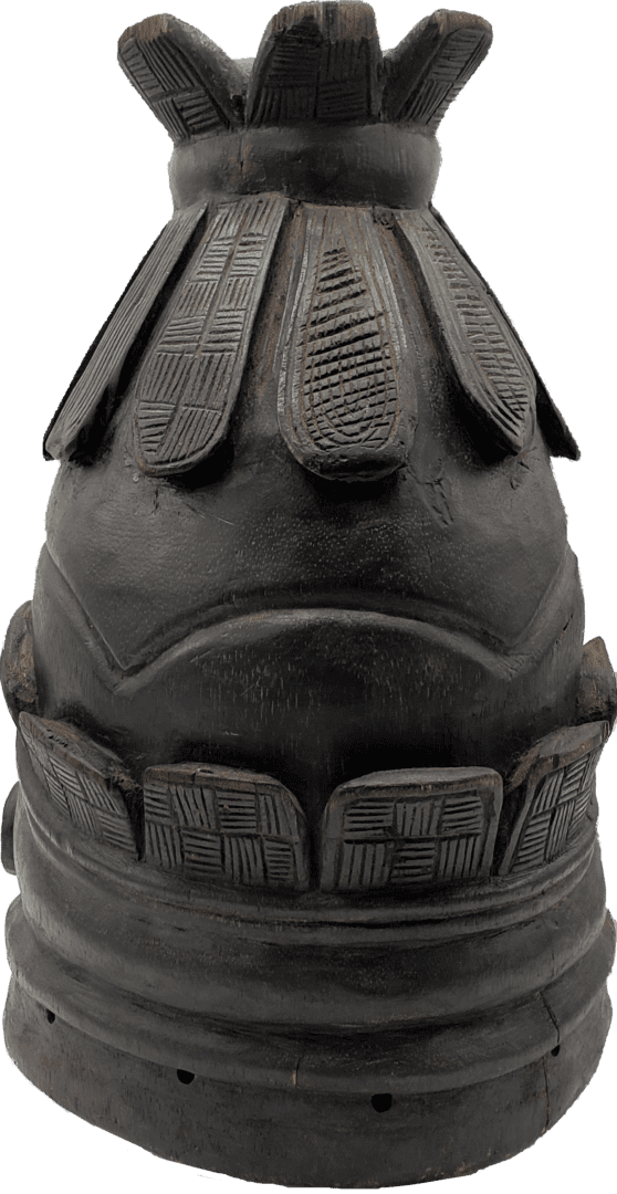 A carved, dark wooden helmet mask featuring layered decorative patterns and circular vents around the base.