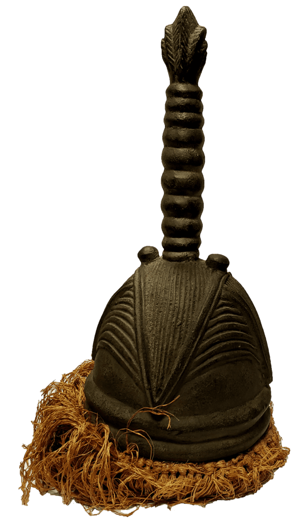 A dark, dome-shaped carved wooden helmet with a central ribbed spire, resting on a base of frayed tan fibers.
