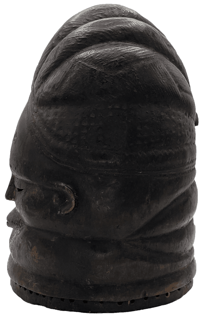 A dark-colored, cylindrical stone carving depicting a stylized, human-like face with horizontal folds and a broad cap.