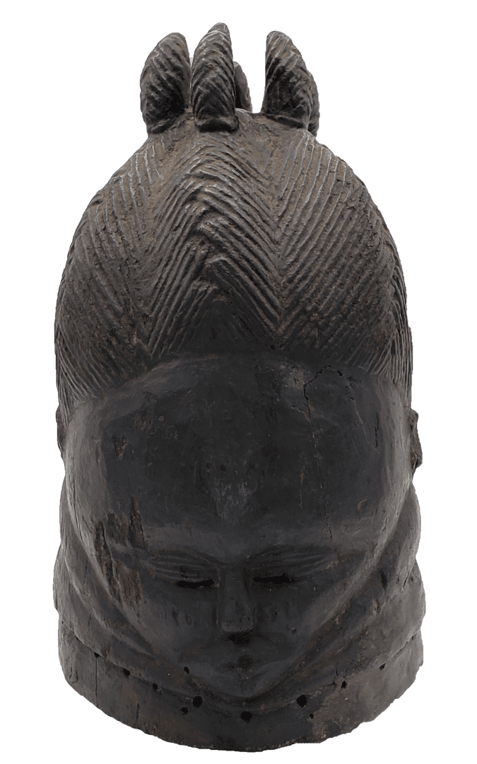 A dark, carved wooden head sculpture with intricate, braided hair patterns and three distinct tufts on top.