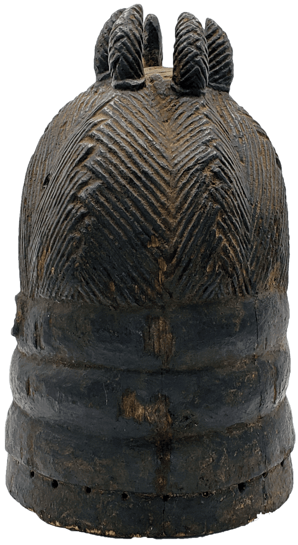 A dark, carved wooden helmet or mask topper with a textured herringbone pattern and five rounded projections on top.