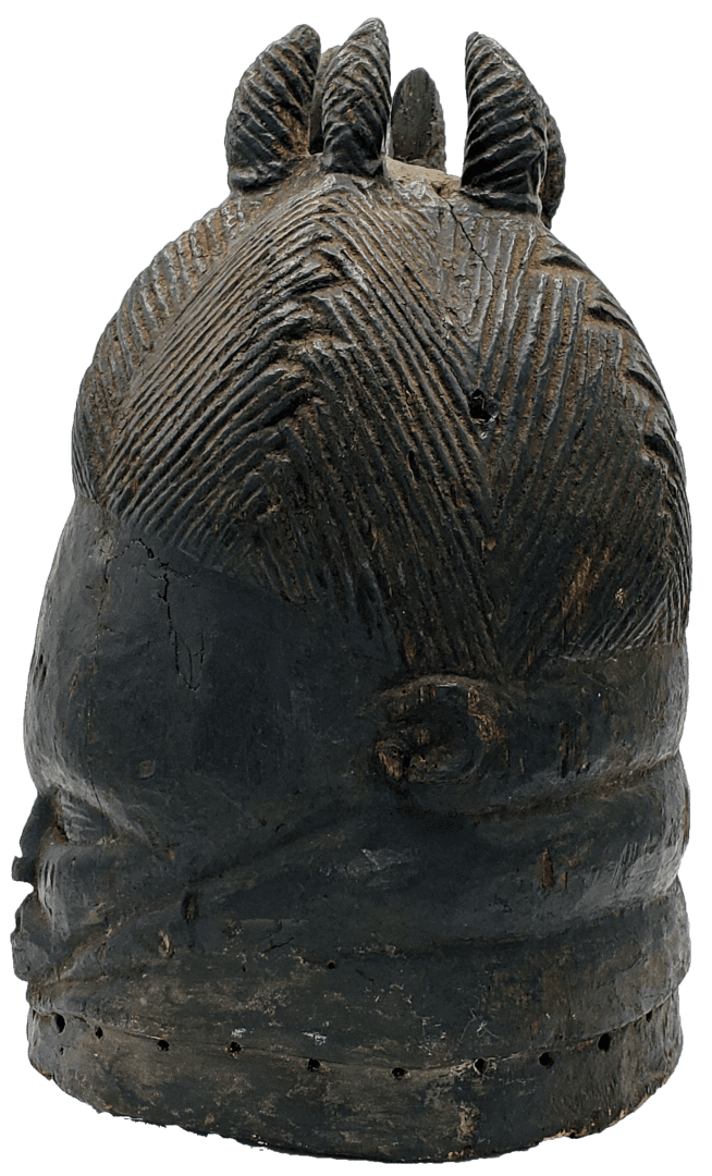 A carved, dark wooden mask depicting a stylized head with intricate hair textures and small protrusions on top.