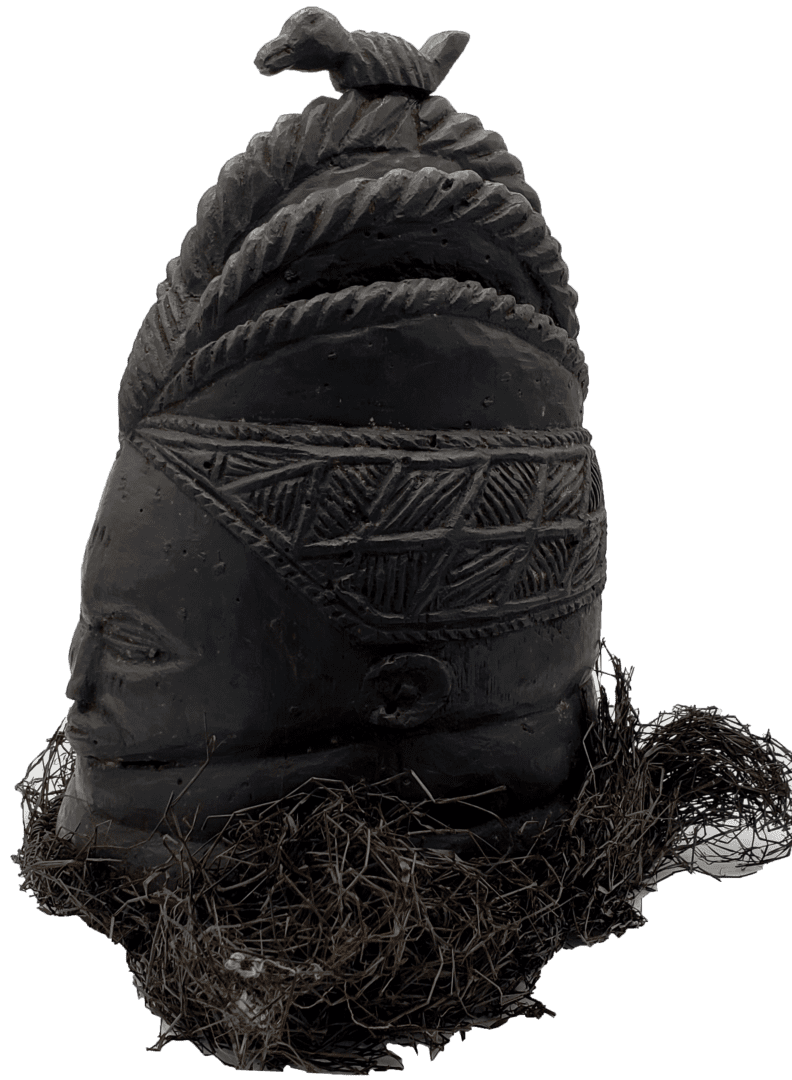 A black, carved wooden sculpture of a stylized head with intricate hair patterns.