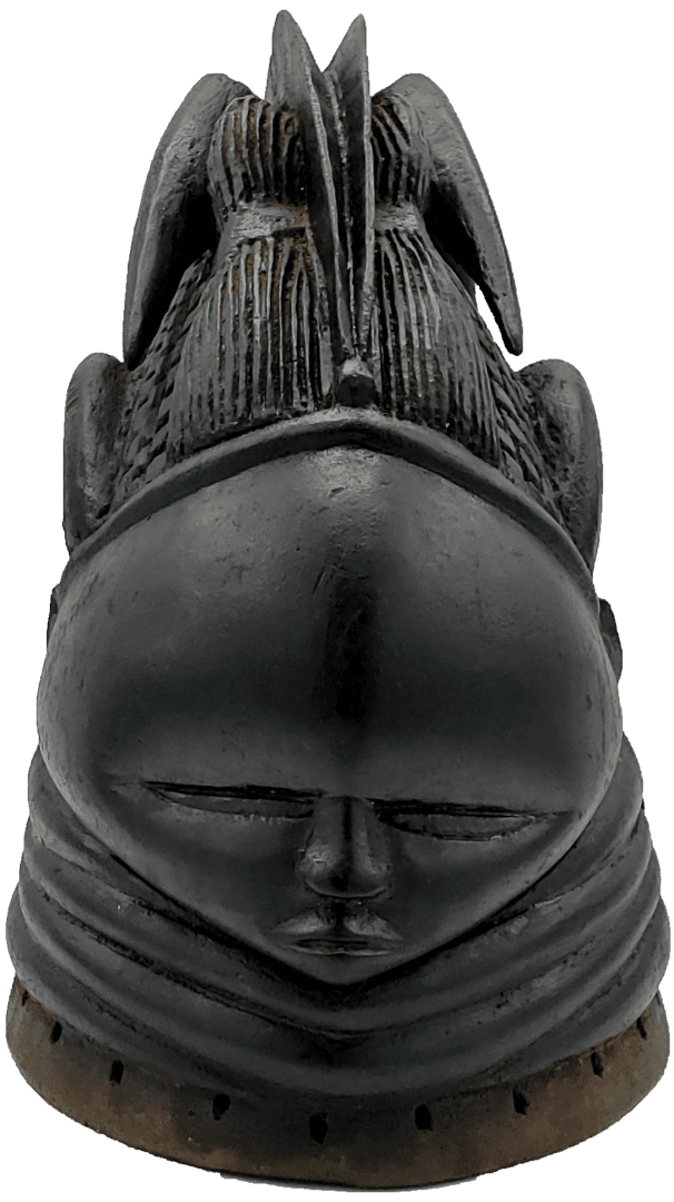 A black, carved wooden helmet mask featuring stylized facial features and an intricate, crested hairstyle.