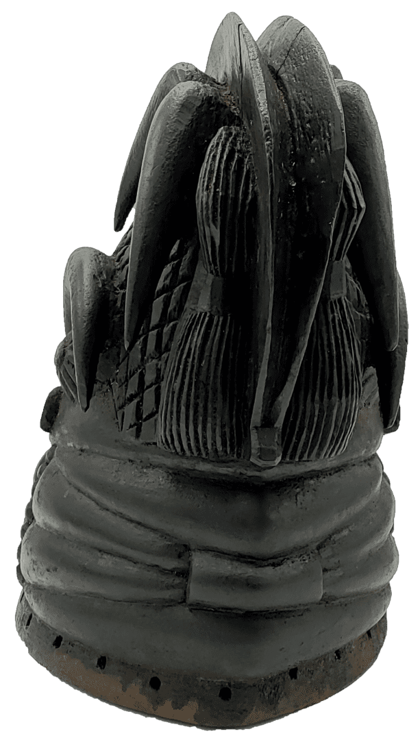 A close-up, back-view shot of a dark, carved stone sculpture showing elaborate braided hair and patterned headwear.
