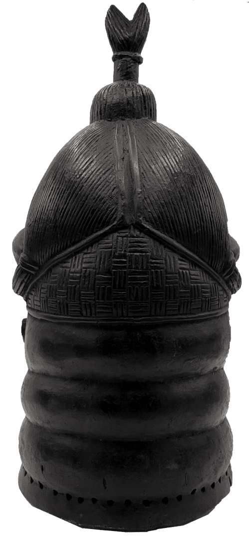 A black, carved wooden headgear or helmet with textured patterns and a small, pointed finial on top.