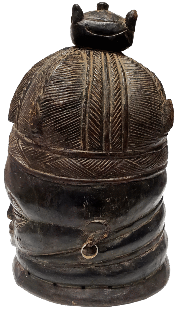 A dark brown carved wooden sculpture of a head wearing an intricate, textured cap and a small metal loop on the neck.
