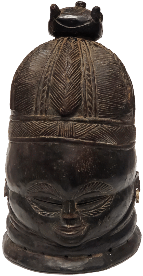 A dark, carved wooden helmet mask featuring an intricate hairstyle, stylized facial features, and a small finial top.