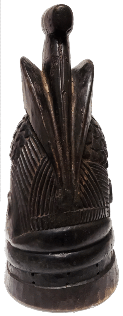 A dark-colored, cylindrical wooden carving with a textured base, ribbed midsection, and a stylized, pointed top piece.