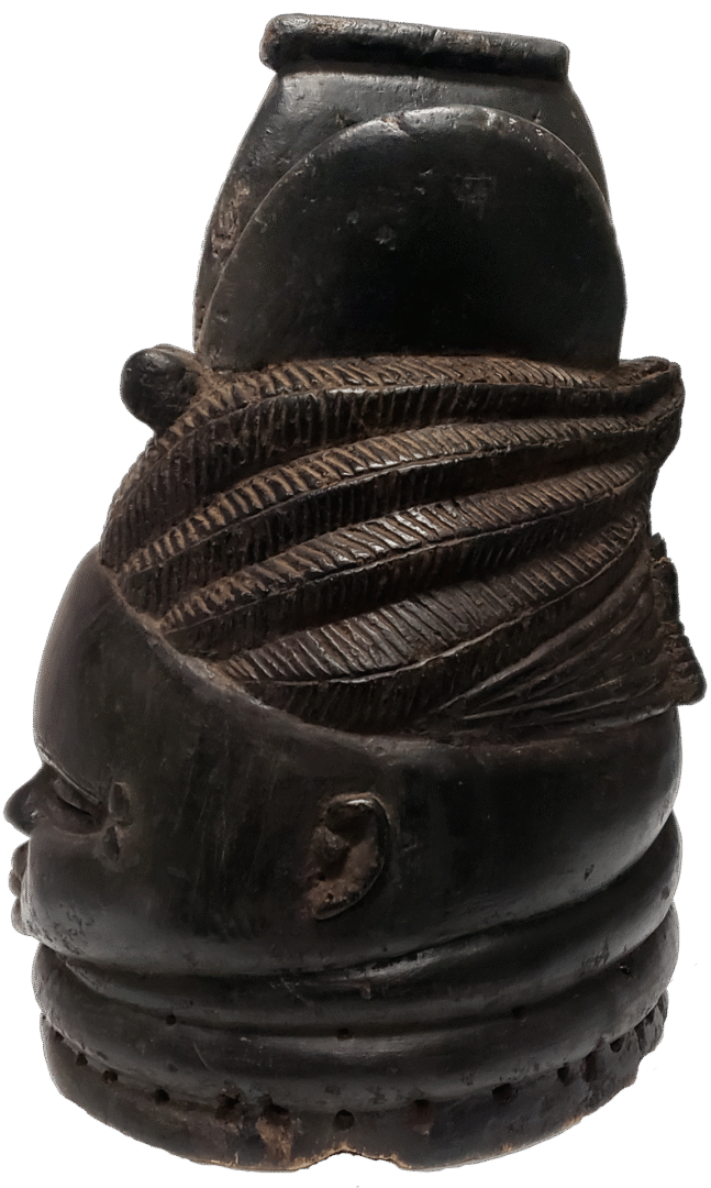 Dark, carved wooden sculpture of a head with detailed, textured hair and neck rings, displayed on a plain white background.